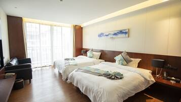 Quarto de hotel com duas camas, uma mesa, uma cadeira, uma televisão e uma janela com cortinas.