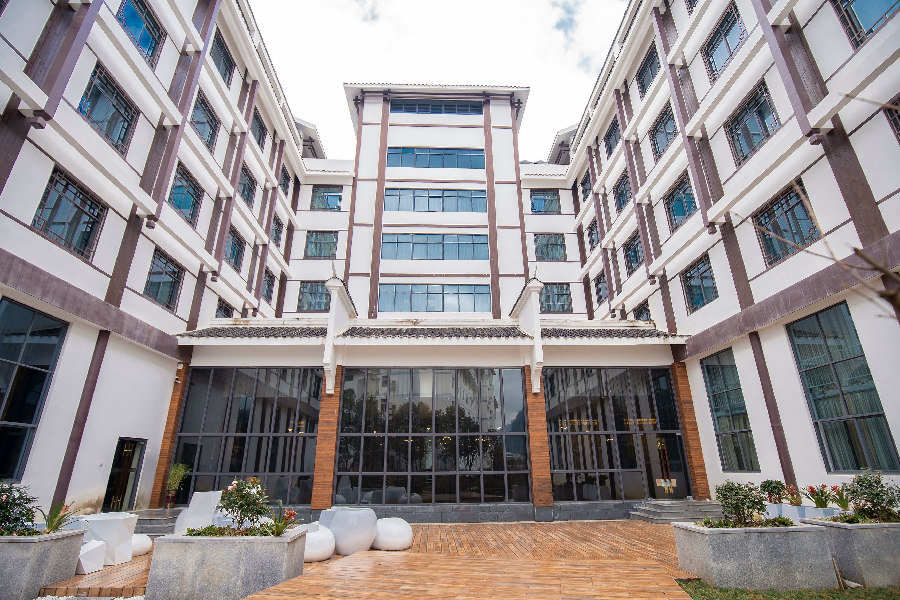 A modern building with a central atrium, large windows, and outdoor seating areas.