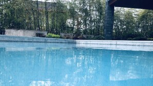 A clear swimming pool with a stone structure in the background and surrounding greenery. - Best Western Plus Qingxinyuan Hotel Zhangjiajie (Zhangjiajie)