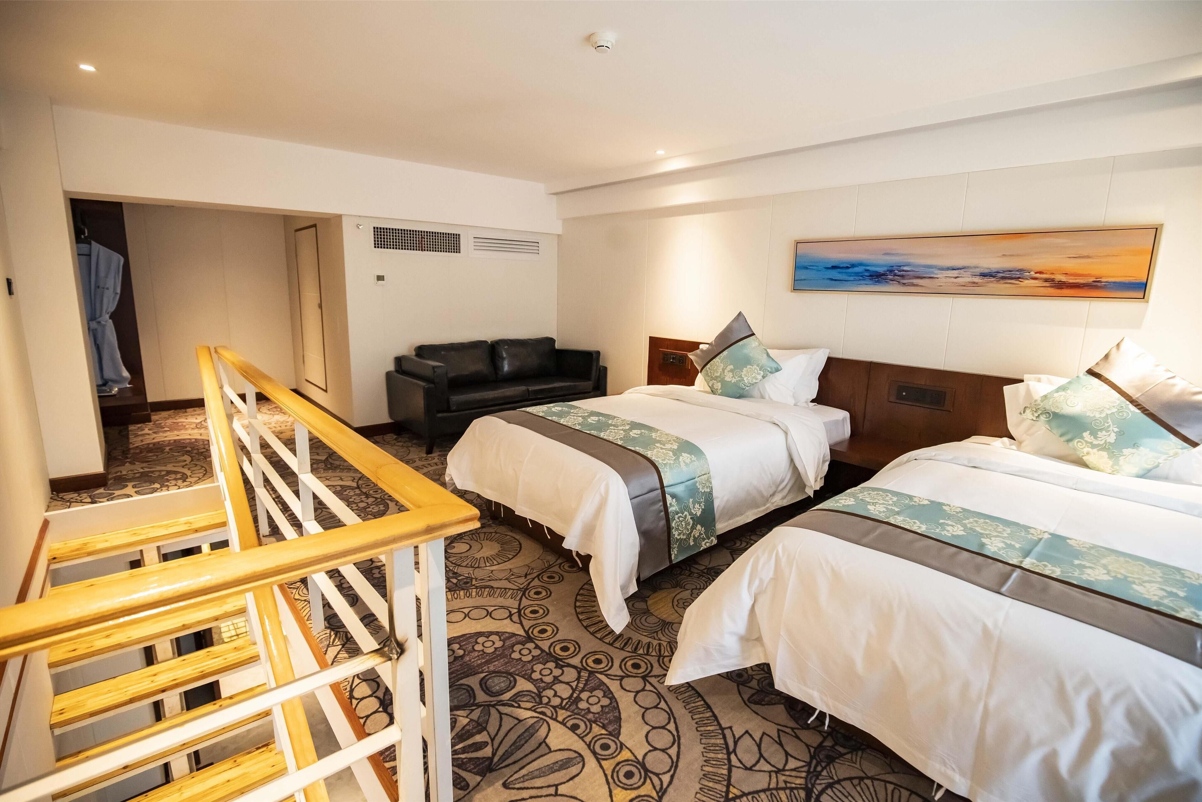 Una habitación de hotel con dos camas, una escalera de madera, un sofá de cuero negro y un cuadro en la pared.