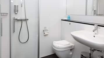 Ett modernt badrum med en dusch som är avskärmad med glasväggar, en vit toalett och ett handfat med en svart bänkskiva.