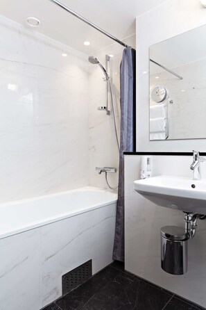Een moderne badkamer met een bad, douche, wastafel en spiegel.