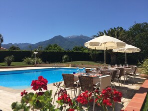 A poolside dining area with tables and chairs, a pool, and a mountain view.