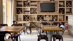 A restaurant with wooden tables and chairs, a wine rack with bottles, and a TV mounted on the wall. - Best Western Le Vauban (Prades)