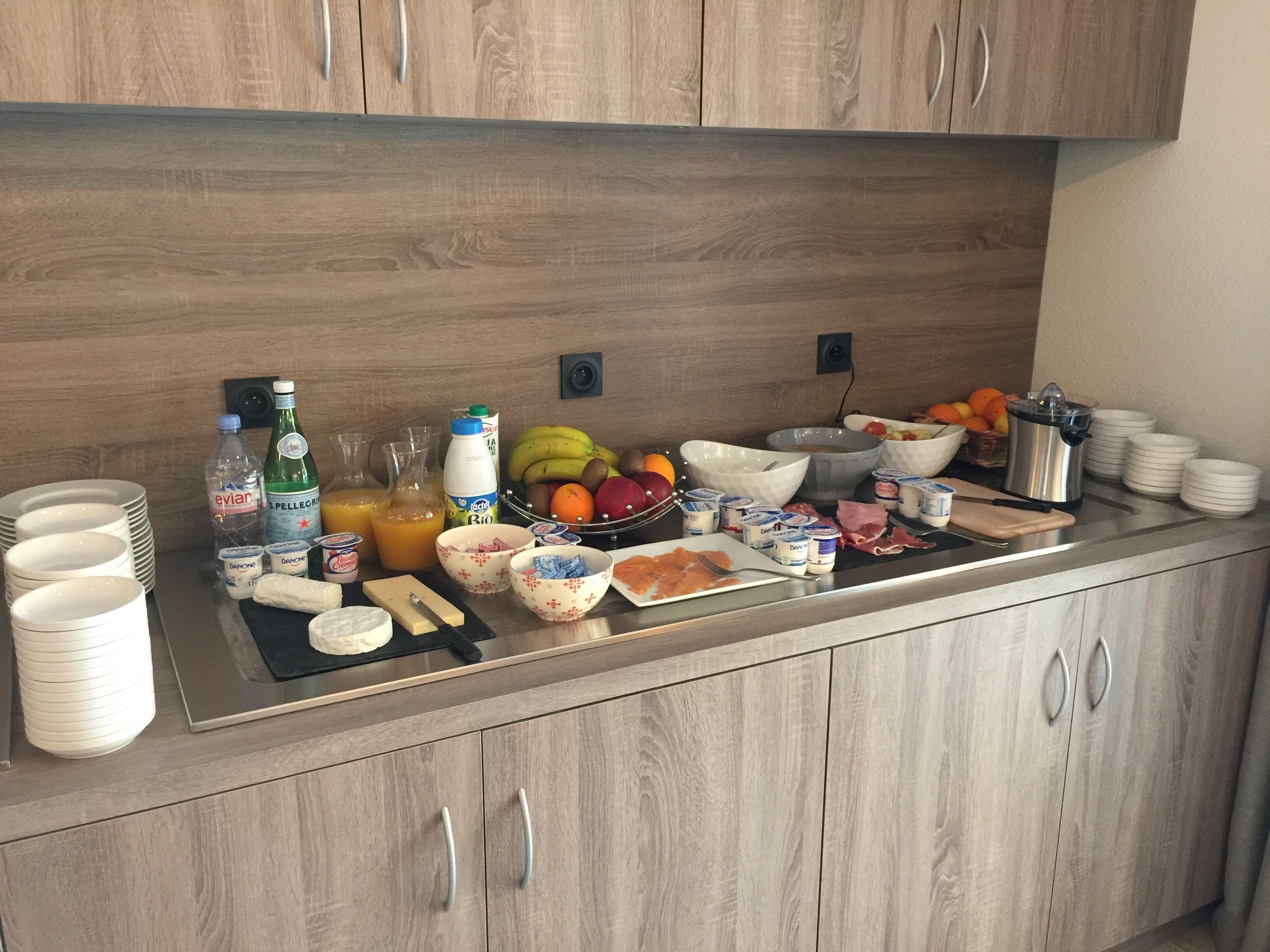 Un plan de travail de cuisine avec divers aliments pour le petit-déjeuner, notamment des fruits, des produits laitiers et des condiments.