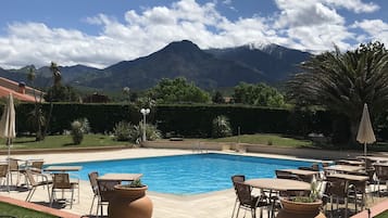 Una piscina al aire libre, sombrillas, sillones reclinables de piscina