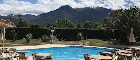 Una piscina al aire libre, sombrillas, sillones reclinables de piscina
