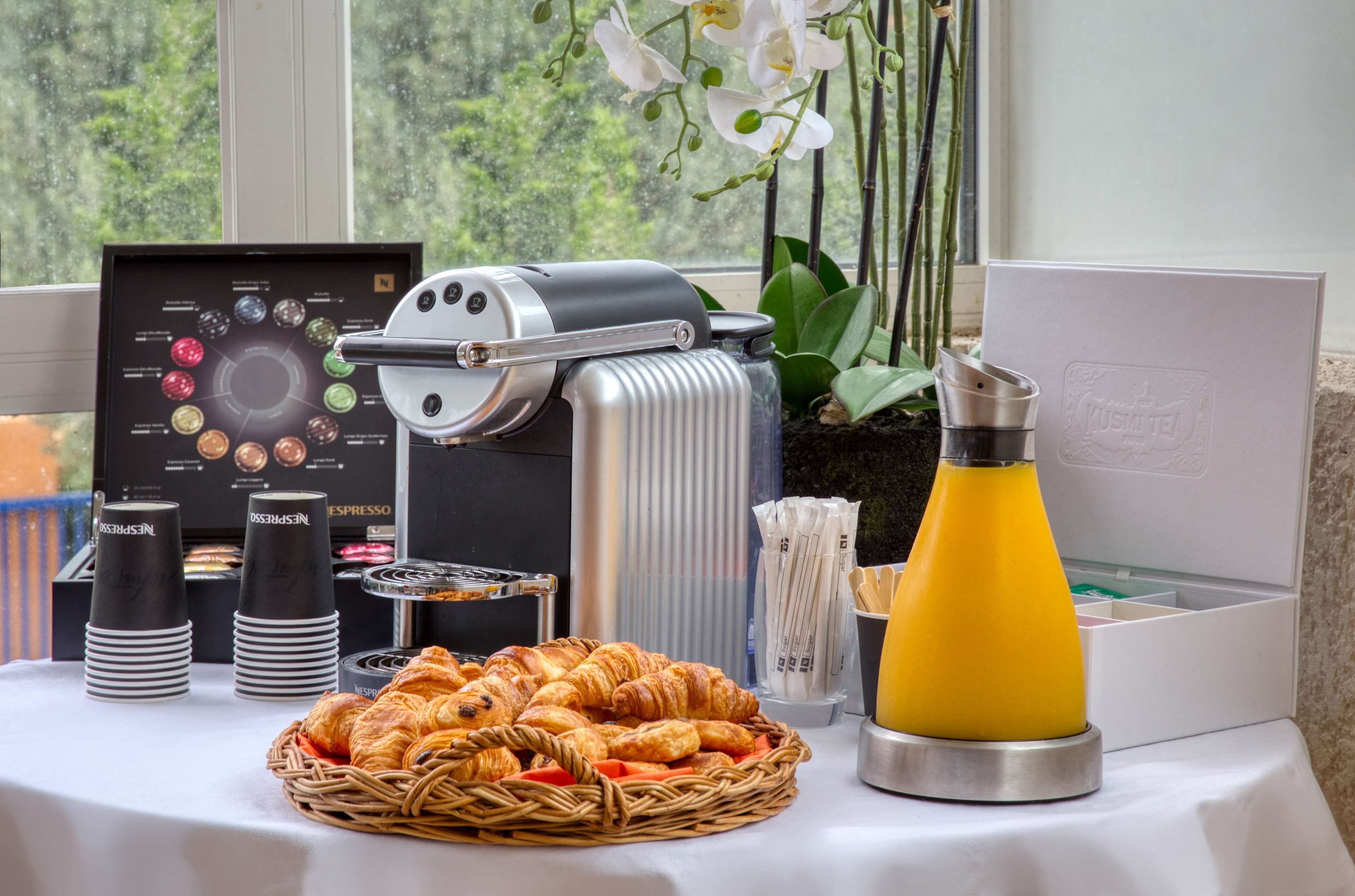 Un buffet de petit-déjeuner comprenant une machine à café, des croissants et un distributeur de jus.