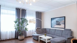 Una sala de estar moderna con un sofá seccional gris, una mesa de centro blanca y una planta grande en maceta.