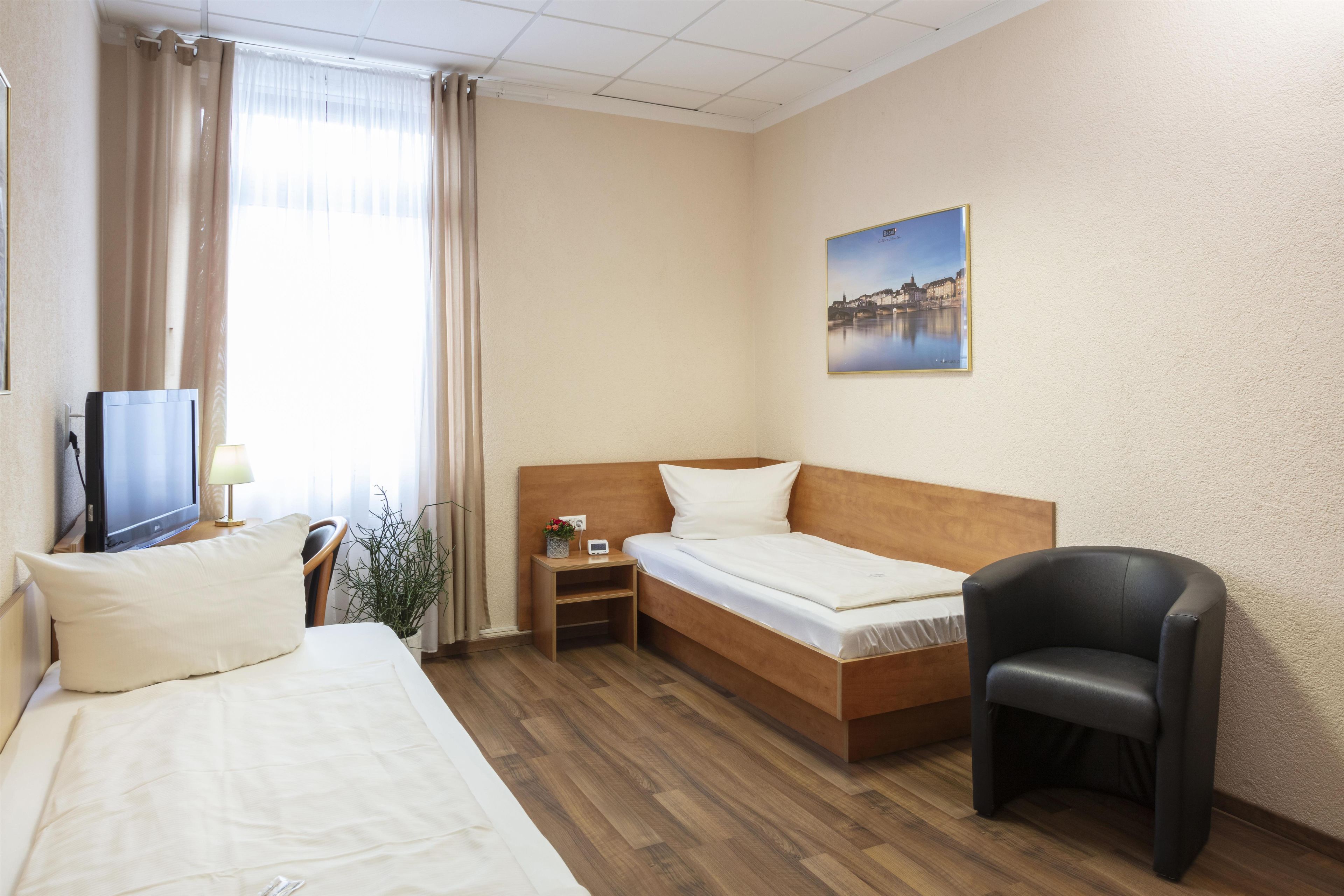 Une chambre d’hôtel avec deux lits, une télévision, un bureau, une chaise et un tableau au mur.
