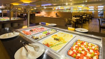 A buffet with various food options, including meats, cheeses, and salads.