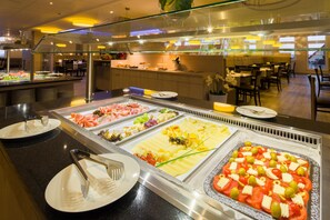 Un bufé con diversas opciones de comida, incluyendo carnes, quesos y ensaladas.