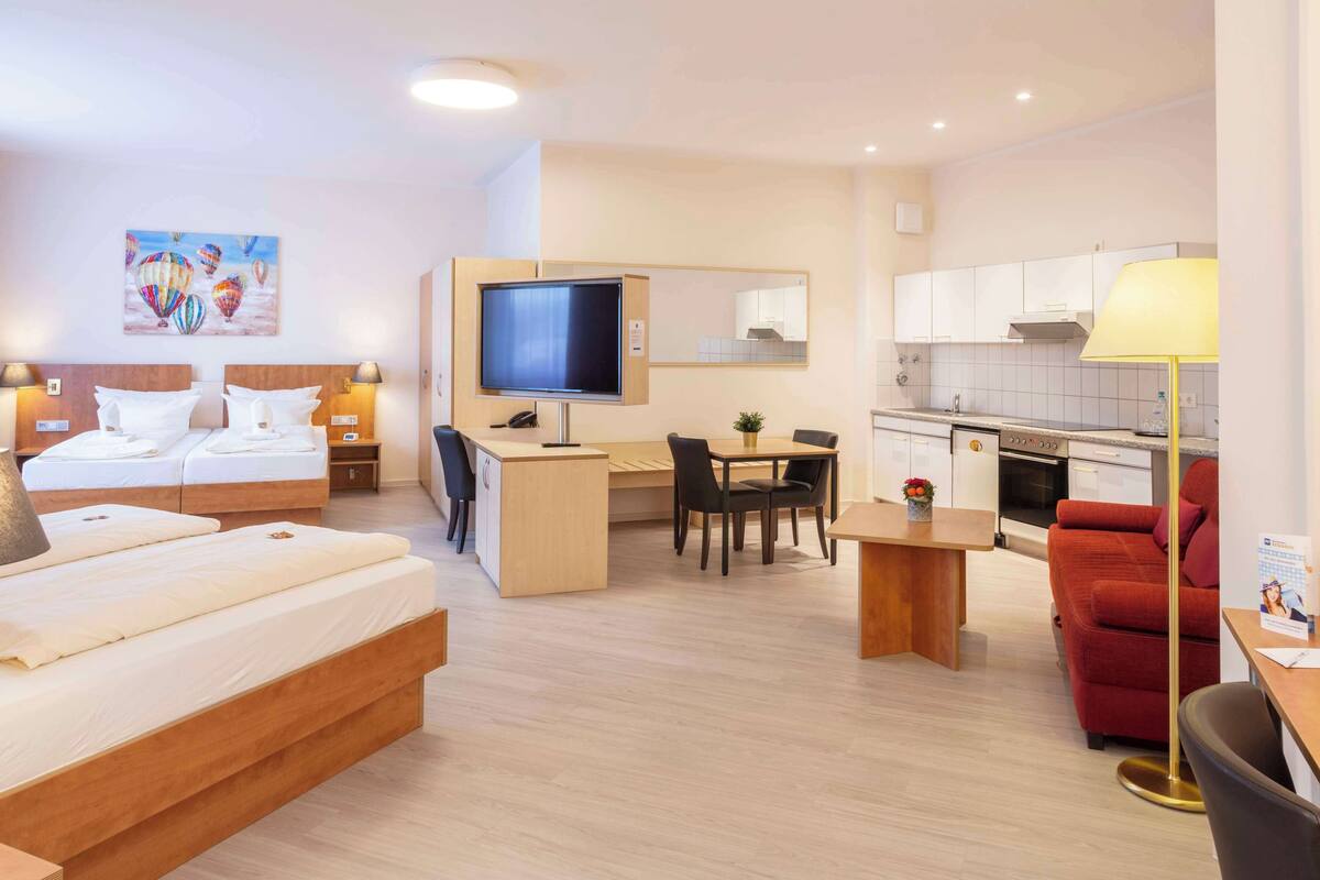 Habitación de hotel con cama, escritorio, silla y kitchenette.