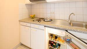 A kitchen with white cabinets, a granite countertop, a built-in oven, a sink, and a wine cooler stocked with bottles. - Best Western Hotel Dreilaenderbruecke (Weil am Rhein)