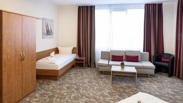 Ein Hotelzimmer mit Bett, einer Couch, einem Sessel, einem Couchtisch und einem Kleiderschrank.