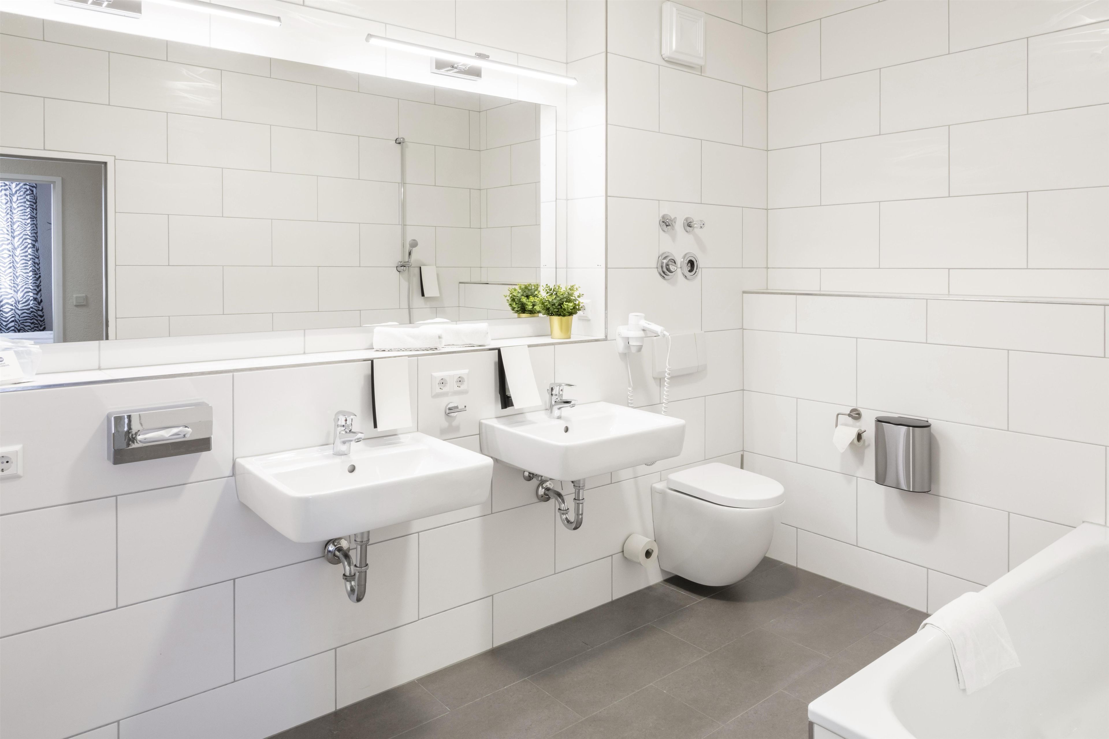 A modern bathroom with two sinks, a toilet, and a shower.