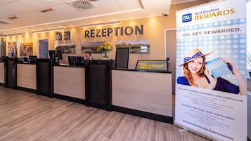 Un área de recepción con mostrador, un cartel grande que anuncia Best Western Rewards y vista al vestíbulo.