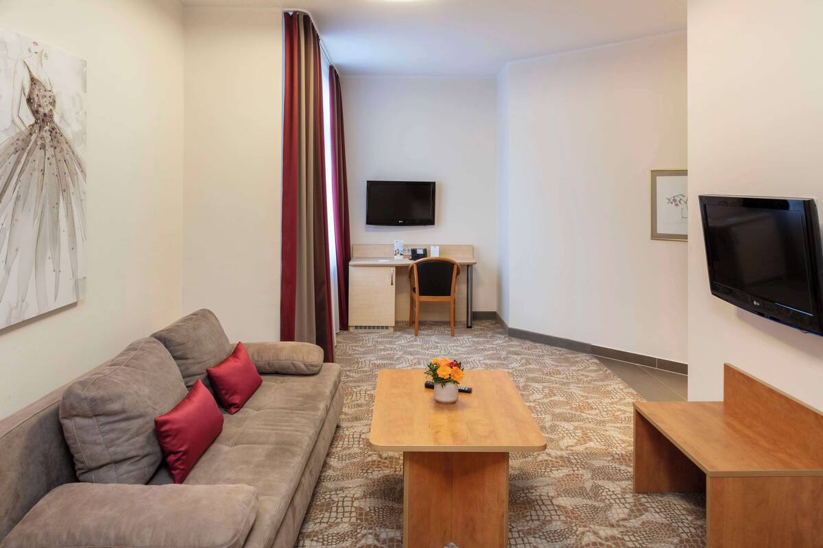 Una sala de estar moderna con un sofá, una mesa de centro con flores, un escritorio y un televisor.