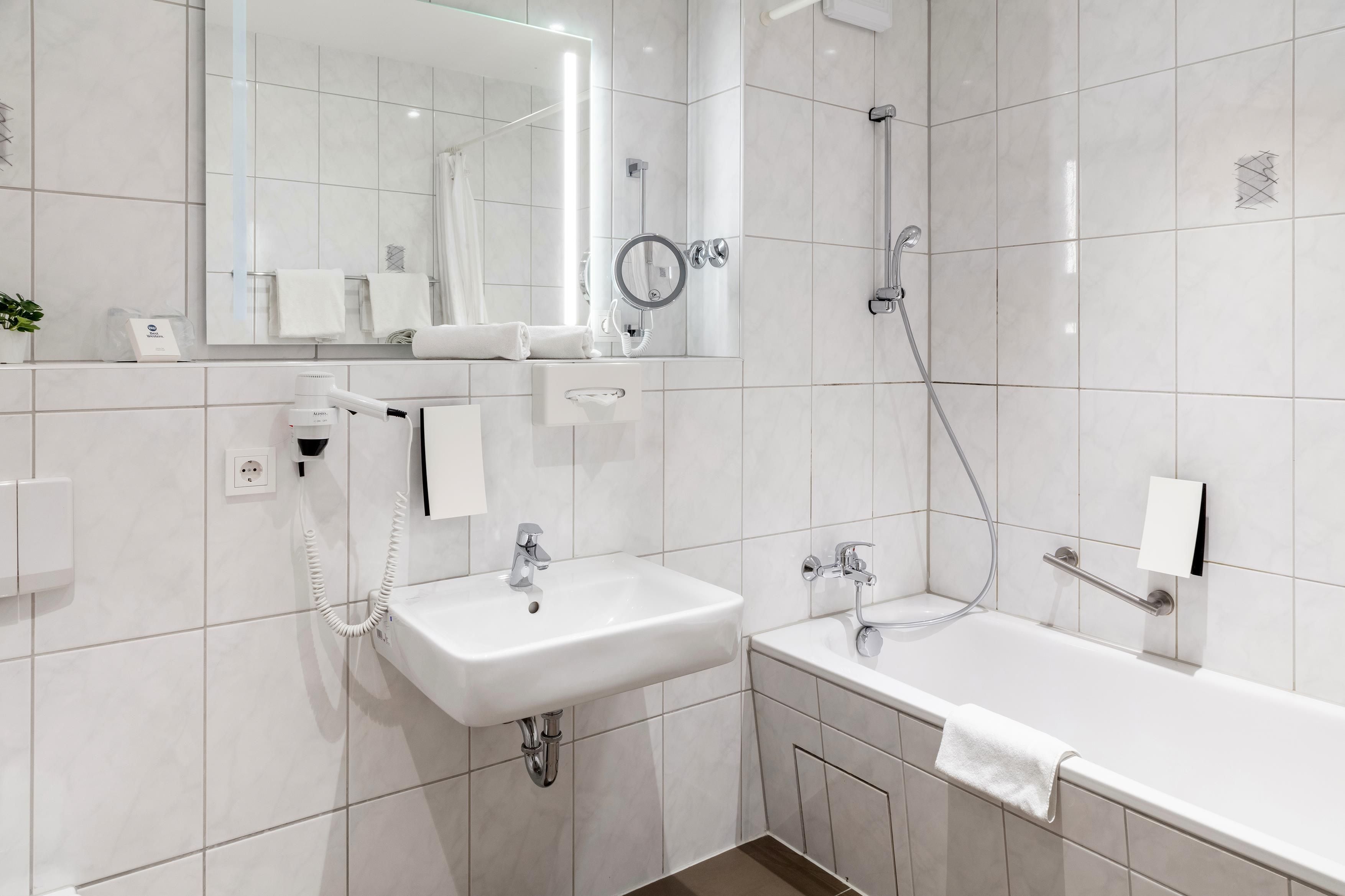 Une salle de bain moderne équipée d’un lavabo, d’un miroir, d’un porte-serviettes et d’une douche.