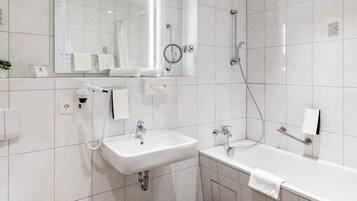 Une salle de bain moderne équipée d’un lavabo, d’un miroir, d’un porte-serviettes et d’une douche.