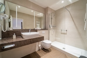 Et stilfuldt badeværelse med vask, toilet og brusekabine i glas.