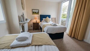 A hotel room with two beds, a desk, a lamp, and a view of the outdoors. - The Clachan Inn (Drymen)