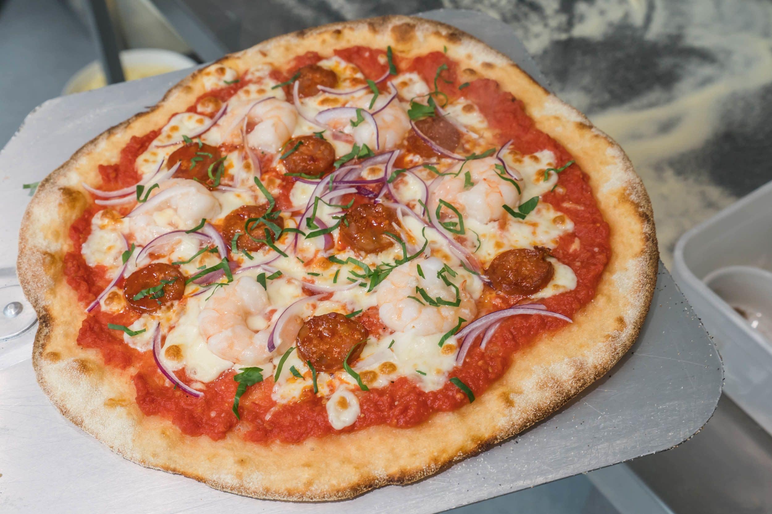 Une pizza garnie, posée sur une surface blanche.