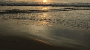 Une plage avec des vagues et un coucher de soleil.