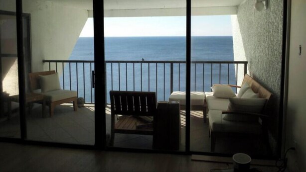 Un balcon avec vue sur la mer, aménagé avec un canapé, des fauteuils et une petite table.