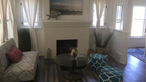 A living room with a fireplace, a sofa, a coffee table, and patterned cushions. - Lake Michigan Beach Cottages (Michigan City)
