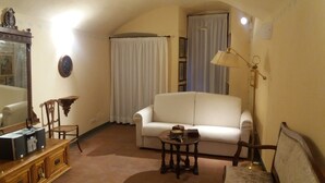 A living room with a white sofa, a wooden coffee table, a lamp, and a mirror. - Michelangelo's retreat, a small residence on the ground floor of a  (Firenze)
