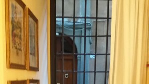 A narrow hallway with a window and a door, framed pictures on the wall, and a pet bed with a bowl. - Michelangelo's retreat, a small residence on the ground floor of a  (Firenze)