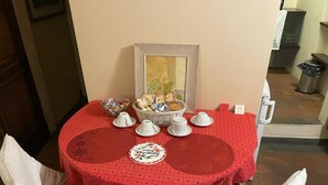 A round table with a red tablecloth, white chairs, and a basket of items. - Michelangelo's retreat, a small residence on the ground floor of a  (Firenze)
