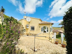 A house with a tiled roof, satellite dish, and a stone patio.
