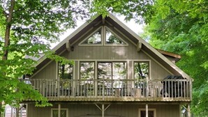 A wooden cabin with a balcony, large windows, and a flat roof. - On the Betsie River, fish off dock, close to Crystal Mountain, trails, lakes! (Thompsonville)