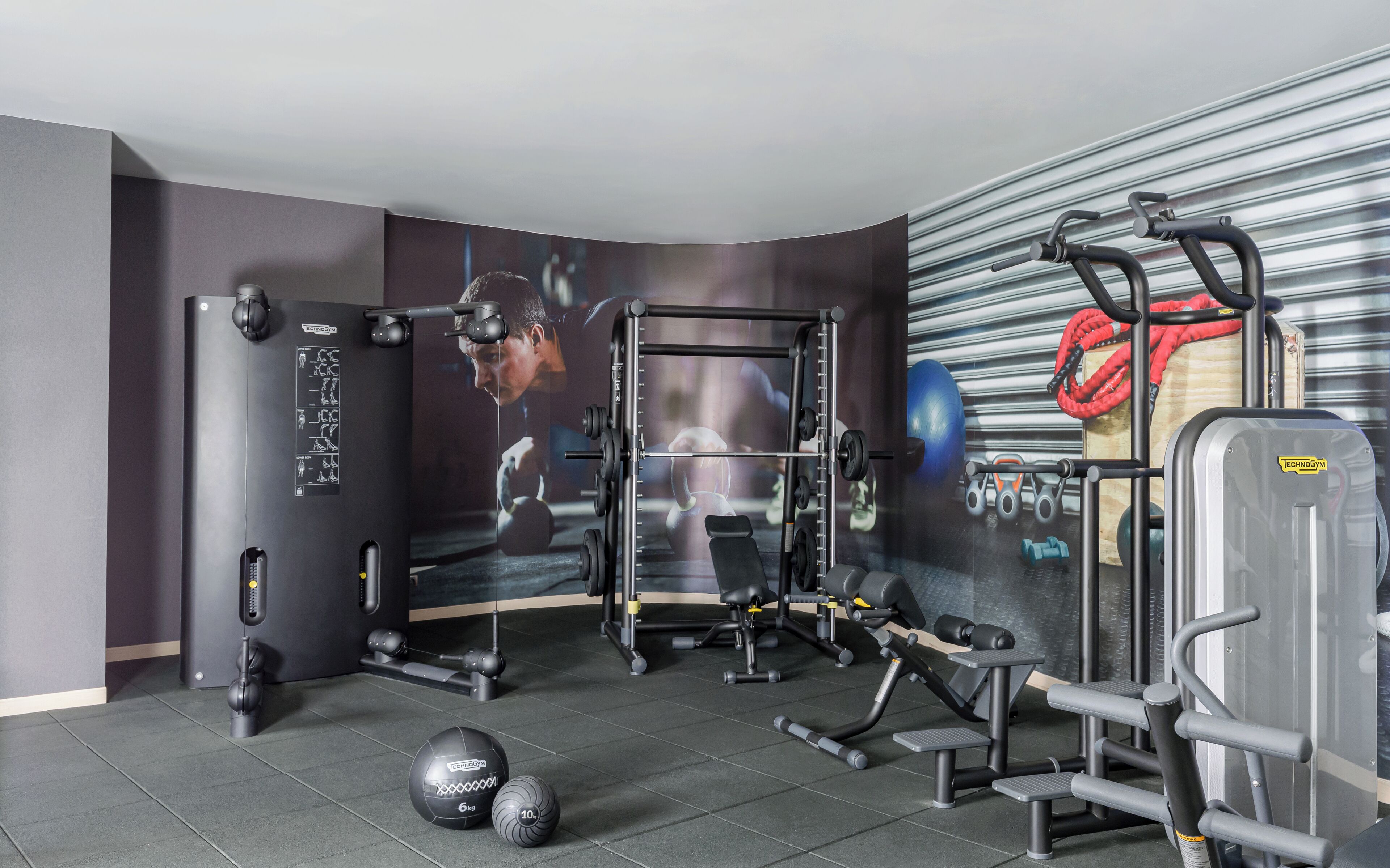 A gym with a squat rack, bench press, and various weights.