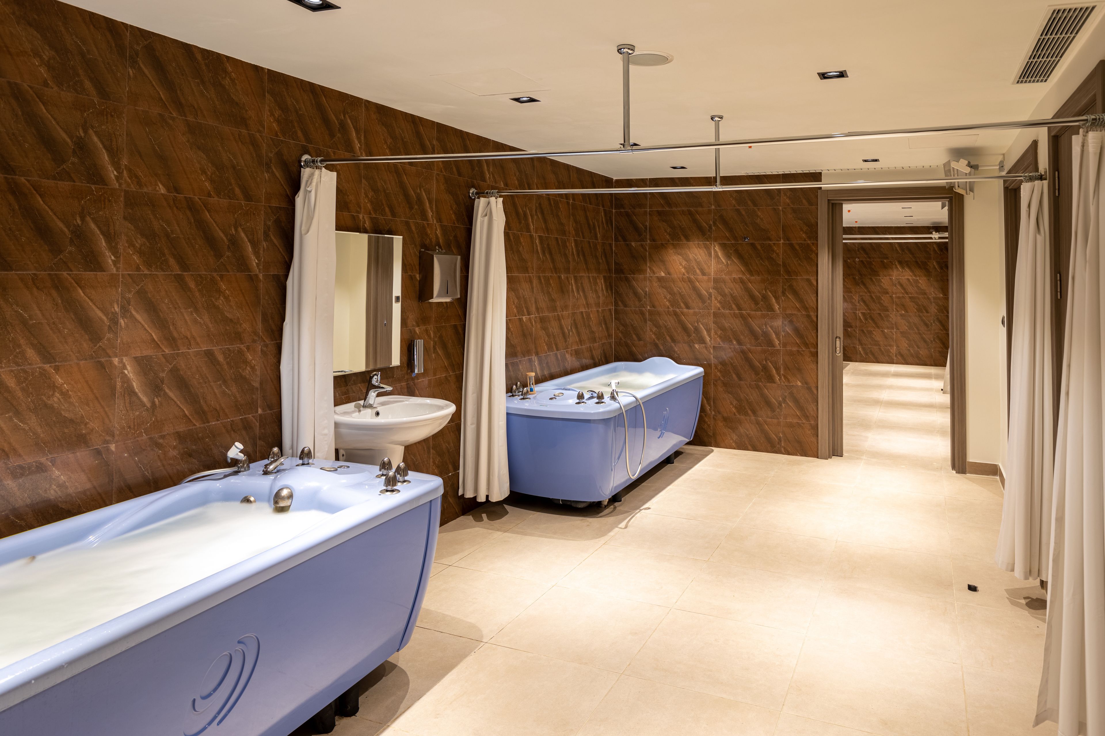 A modern bathroom with a large bathtub, a double sink, and a shower area.