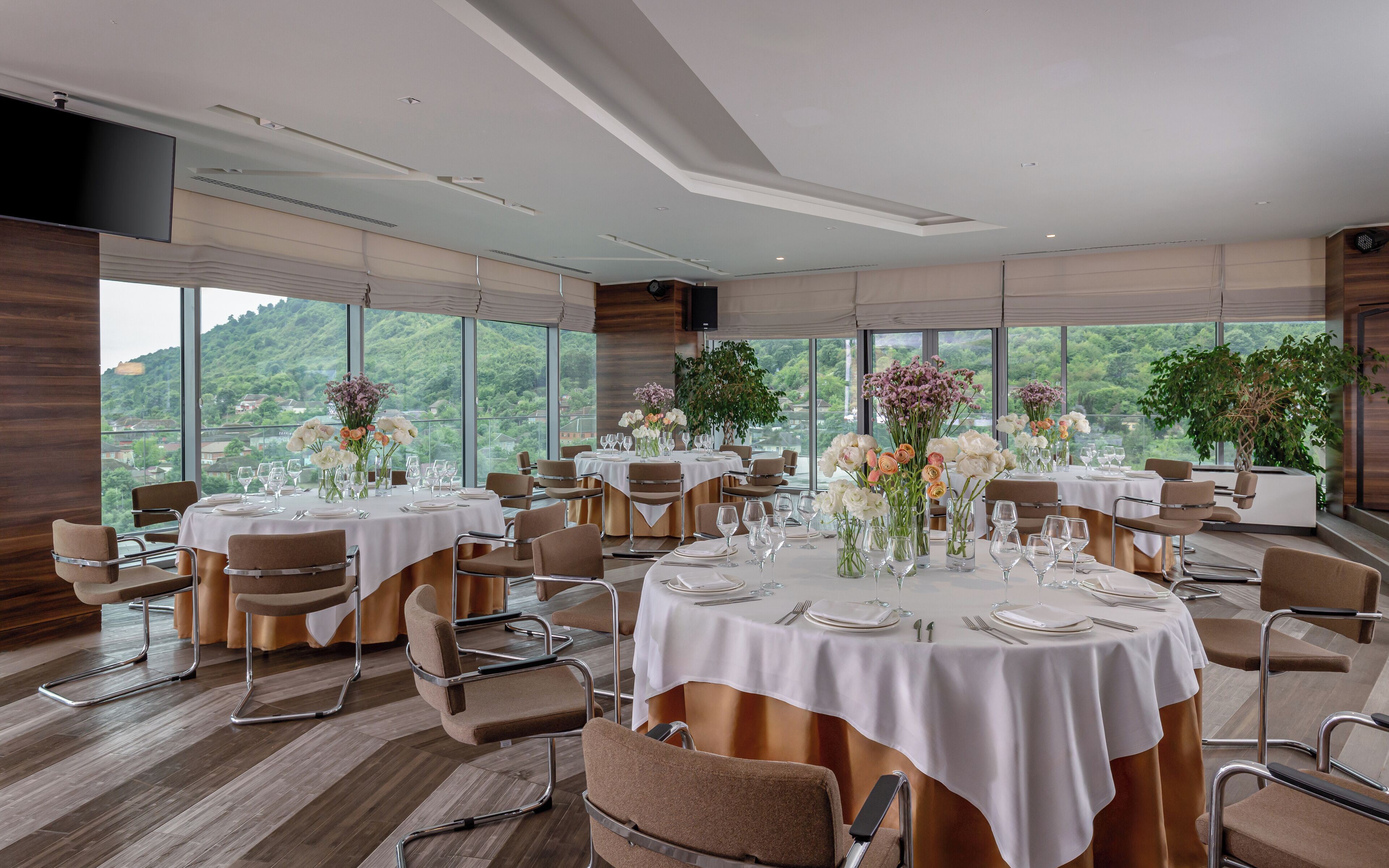 A dining area with round tables, chairs, and floral centerpieces.