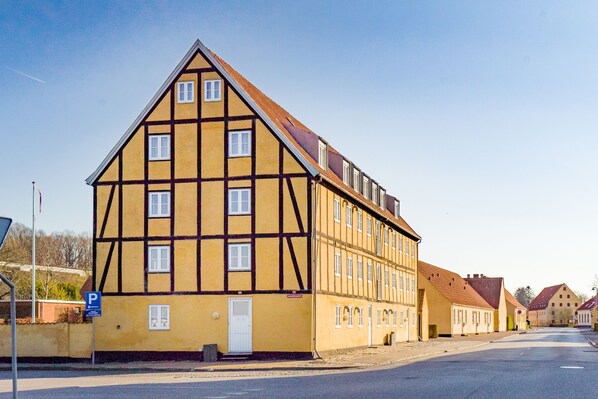 A traditional half-timbered building with multiple windows and a flat roof. - Apartments Bandholm (Bandholm)