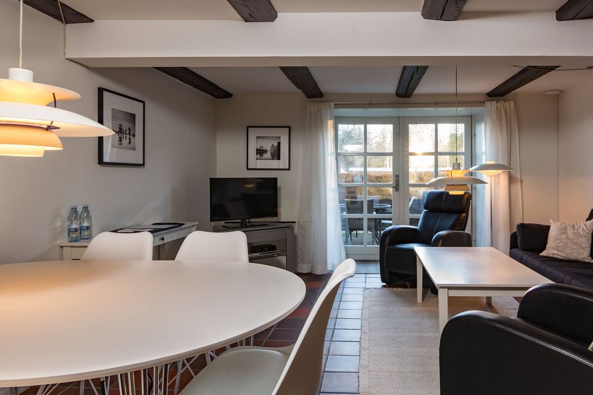 A modern living room with a dining area, a TV, and a large window.