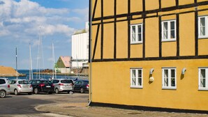 A yellow building with multiple windows and a dock in the background. - Apartments Bandholm (Bandholm)