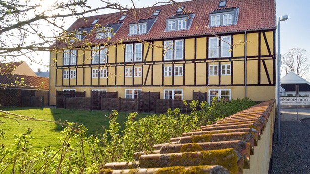 A traditional half-timbered building with multiple windows and a sloped roof. - Apartments Bandholm (Bandholm)