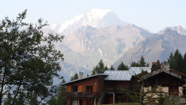 Eine rustikale Lodge mit einem Balkon mit Blick auf eine gebirgige Landschaft.