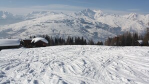 Eine verschneite Berglandschaft mit einer Hütte und Skiabfahrten.