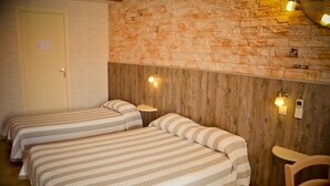 Una habitación con tres camas, paredes de madera y una puerta.