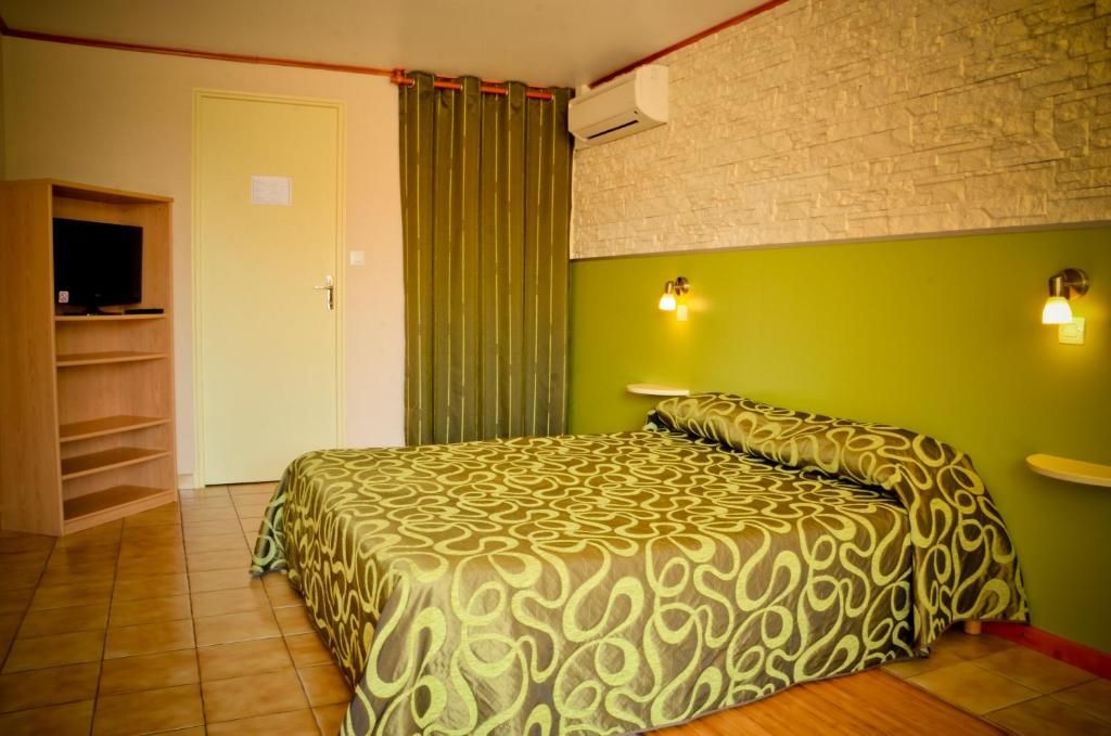 Ein Zimmer mit einem Bett, einem Fernseher, einem Regal und einer Wandklimaanlage.