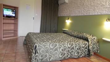Een slaapkamer met een bed, een televisie op een plank, een deur en een wand met een structuur.