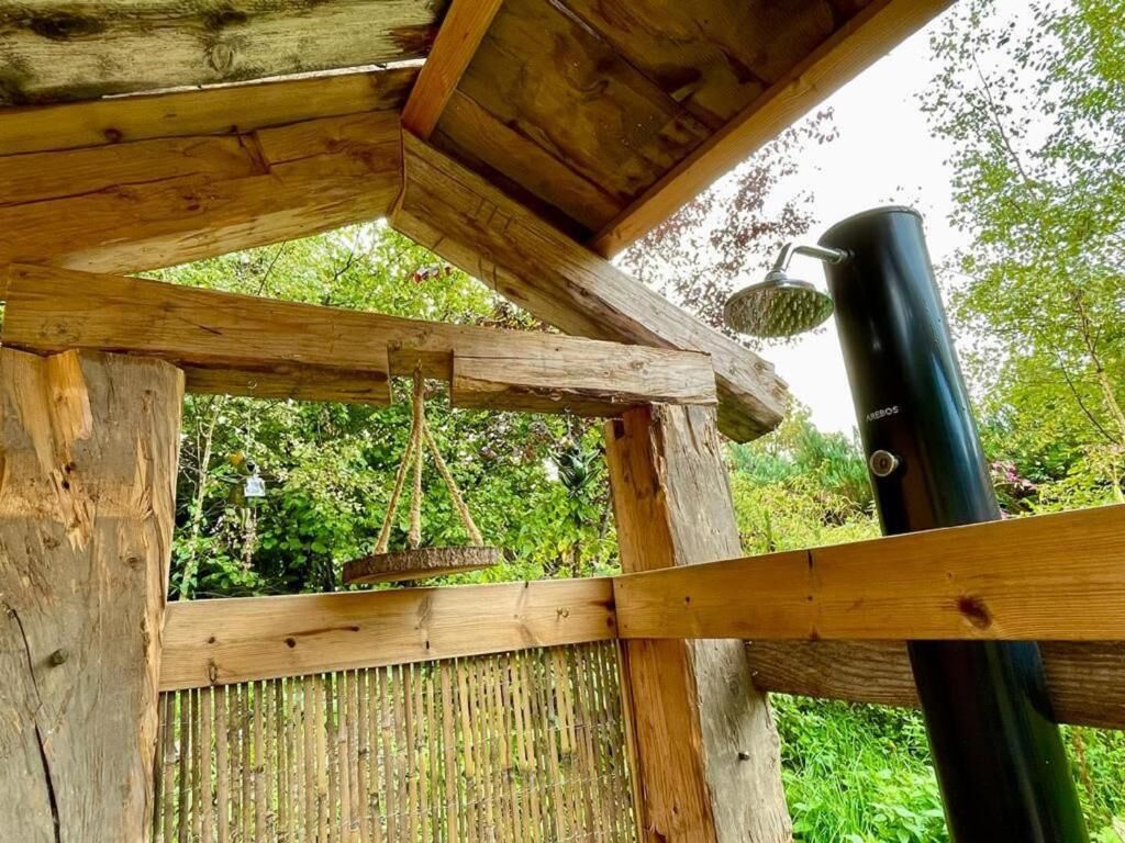 A wooden structure with a hanging swing and a showerhead.