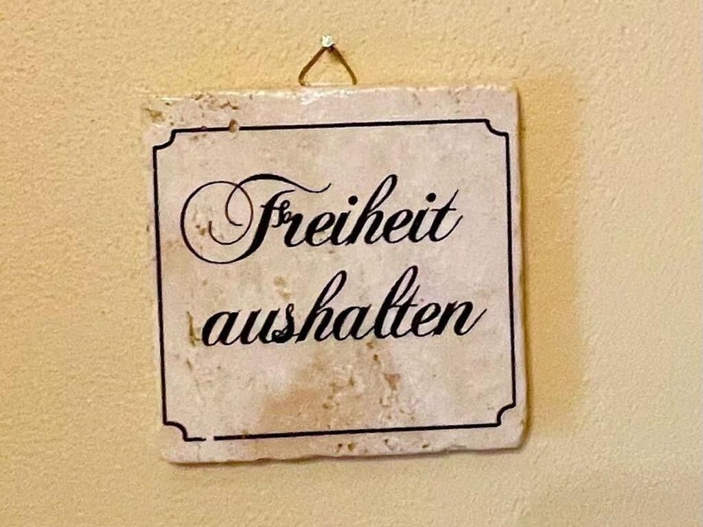 Une affiche portant l’inscription « Freiheit aushalten » est fixée à un mur.