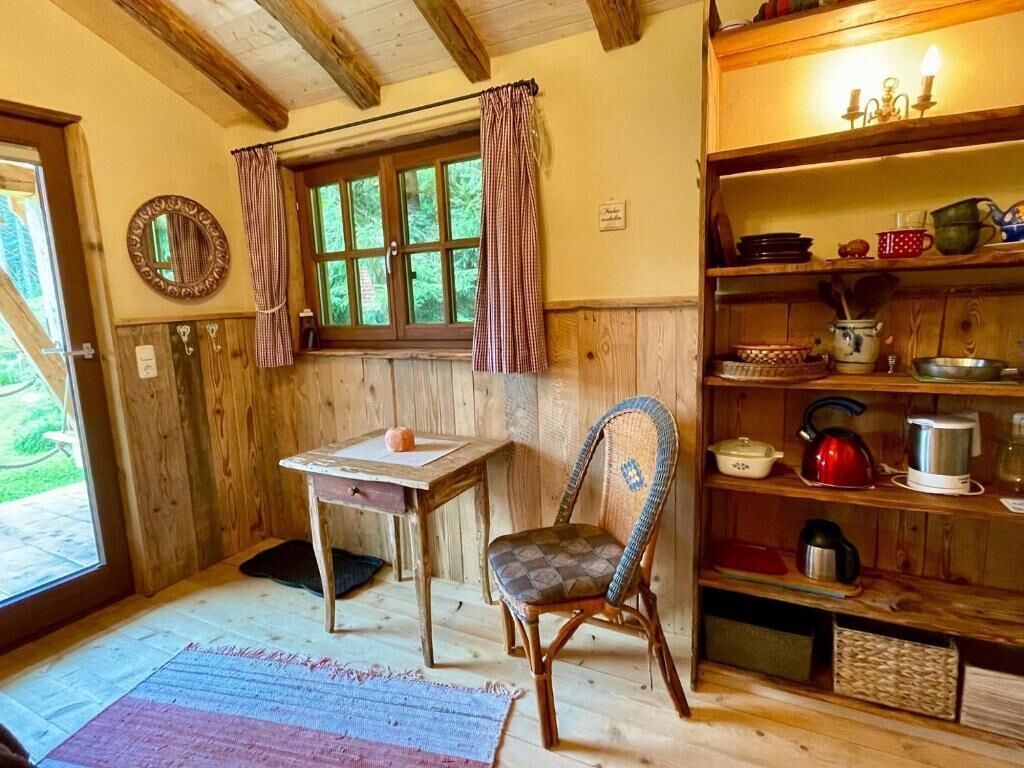 Een houten interieur met een tafel, stoel en planken met keukengerei.